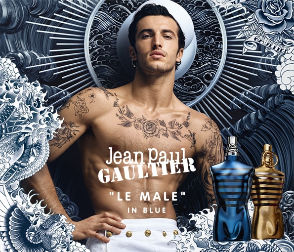 Parfém Jean Paul Gaultier Le Male In Blue s ikonickými modrými a zlatými flakóny na výrazném námořním pozadí.