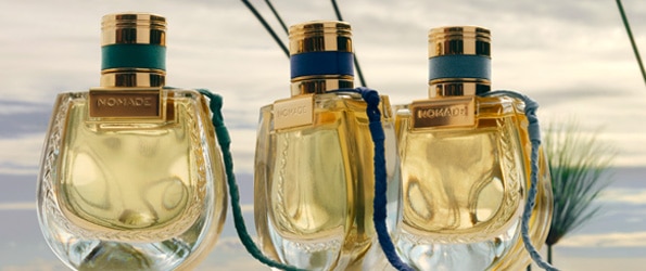 Parfém Chloé Nomade Jardin d’Égypte v elegantním zlatém flakonu na pozadí slunečného rákosí.