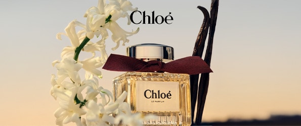 Luxusní parfém Chloé Le Parfum s tmavě červenou stuhou, vanilkovými luskami a květinou na pozadí západu slunce – dámská vůně dostupná online