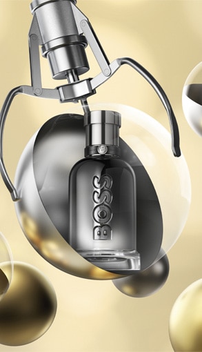 Hugo Boss parfém v elegantním stříbrném flakonu uvnitř vánoční ozdoby na zlatém pozadí.